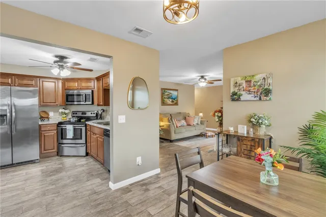 a kitchen with granite countertop stainless steel appliances a stove refrigerator dining table and chairs