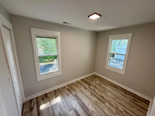 a view of an empty room with wooden floor and a window