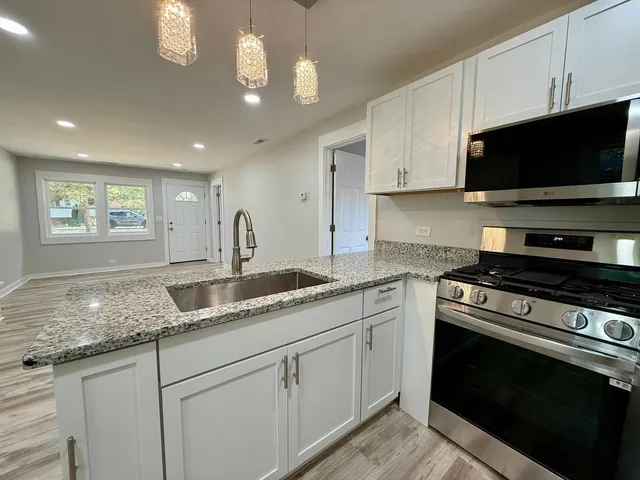 a kitchen with granite countertop a stove a sink and a microwave