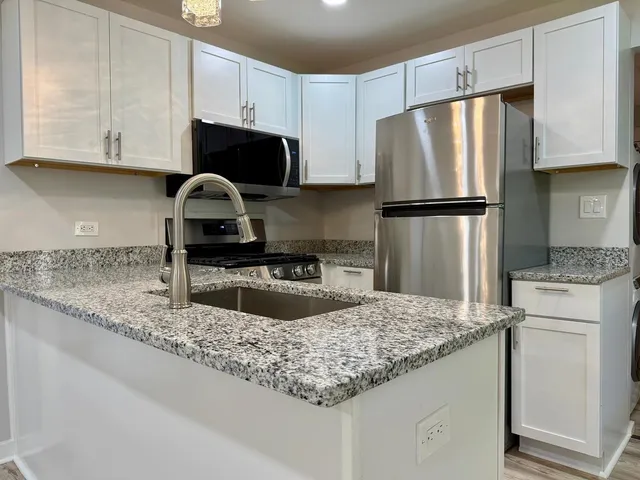 a kitchen with granite countertop a refrigerator sink and microwave