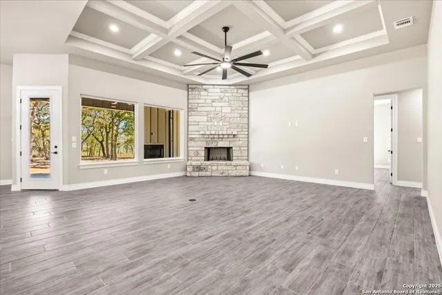 an empty room with wooden floor chandelier fan and windows