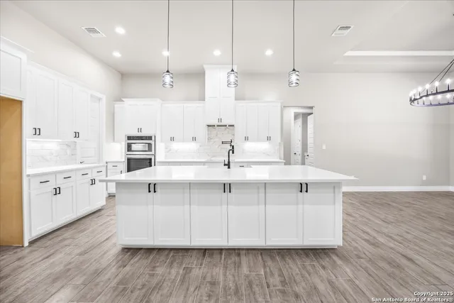 a large white kitchen with kitchen island white cabinets and stainless steel appliances