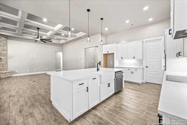 a large white kitchen with lots of counter space wooden floor and stainless steel appliances