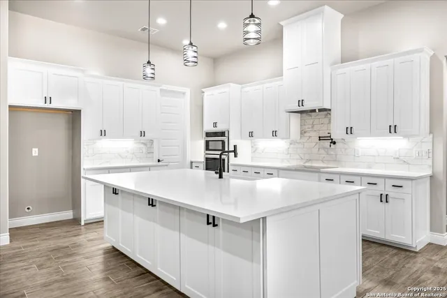 a kitchen with kitchen island white cabinets a sink dishwasher and a stove with wooden floor
