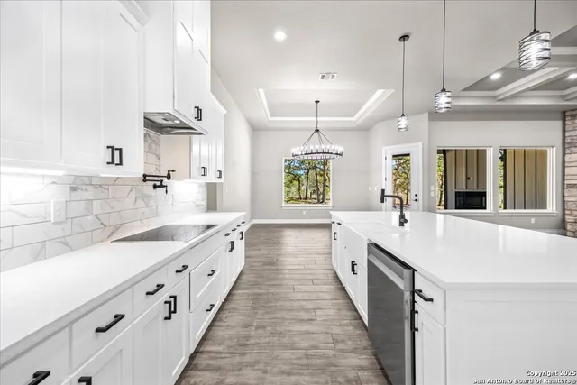 a large white kitchen with lots of counter space wooden floor and stainless steel appliances
