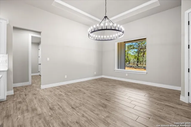 an empty room with wooden floor chandelier and window