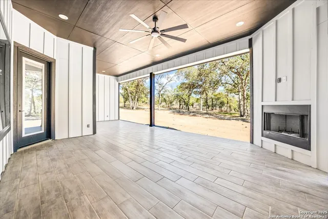 a view of an empty room with a window and a kitchen view