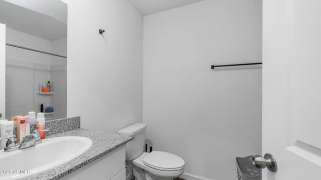 a bathroom with a granite countertop sink toilet and a mirror