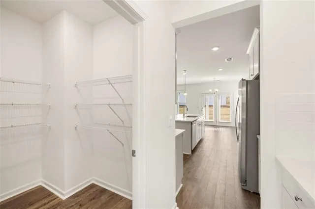 a view of an empty room with wooden floor and a kitchen