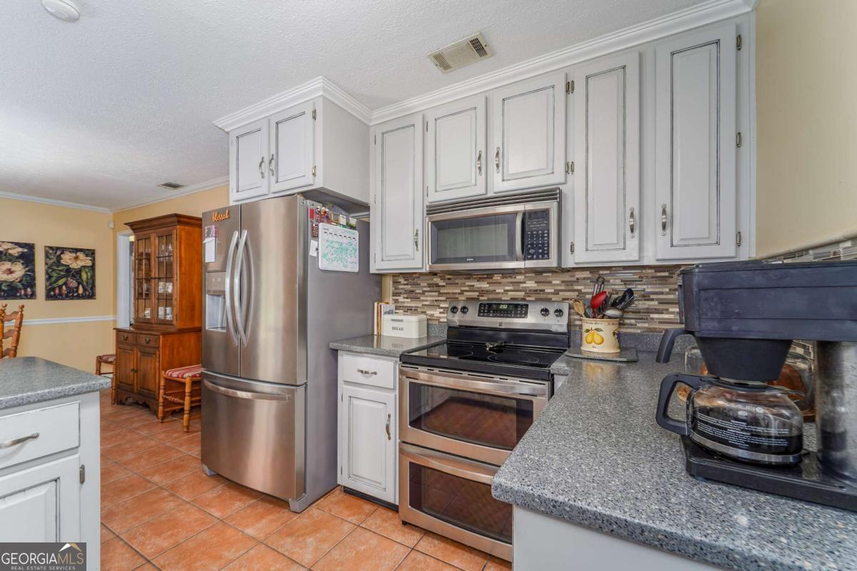1238 Red Keen Road Waycross, GA 31503 - Photo 6 of 37 a kitchen with granite countertop a refrigerator stove and microwave