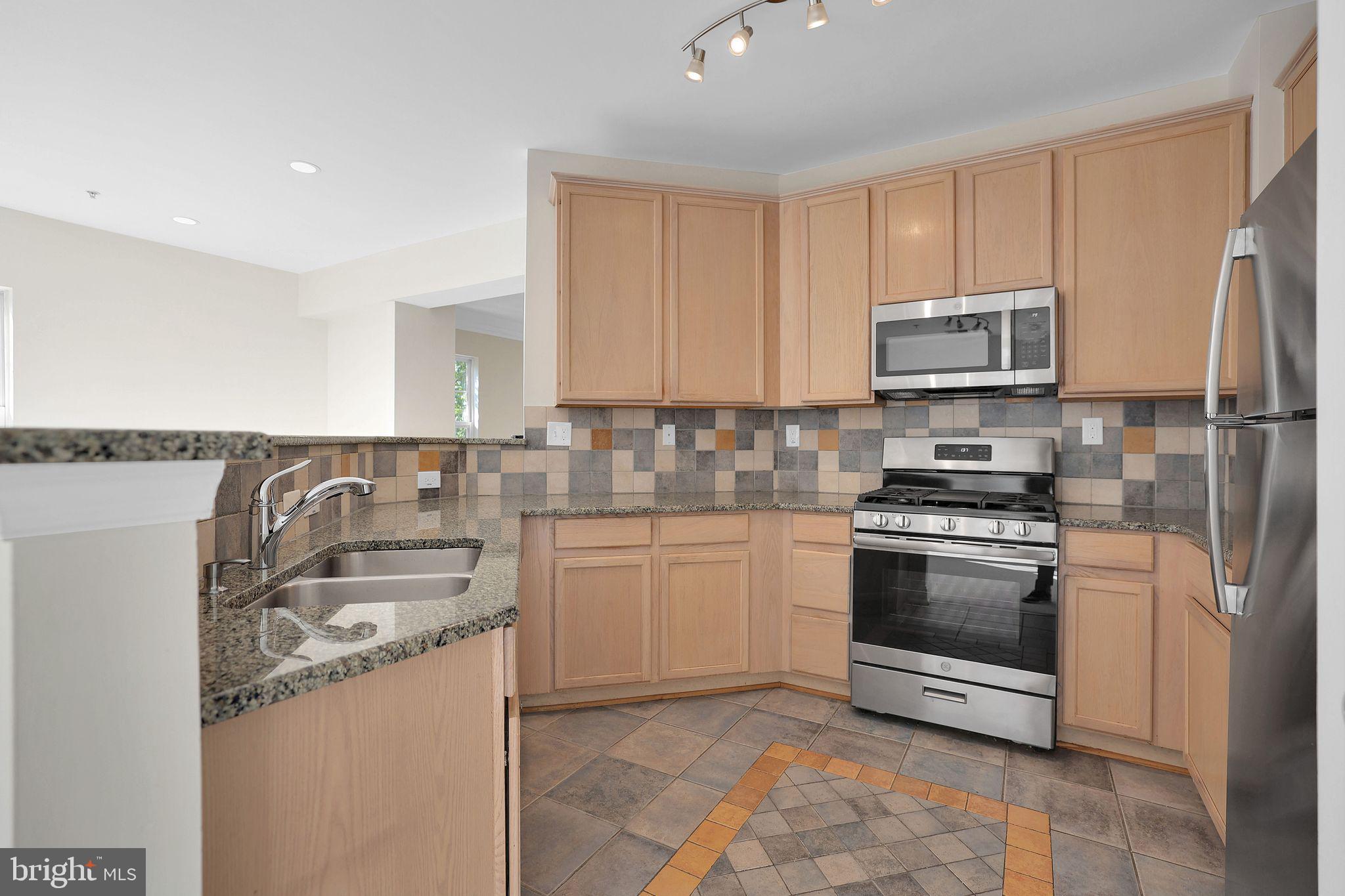 111 A Chevy Chase Street, Unit 111A Gaithersburg, MD 20878 - Photo 14 of 47 a kitchen with stainless steel appliances granite countertop a sink stove and refrigerator
