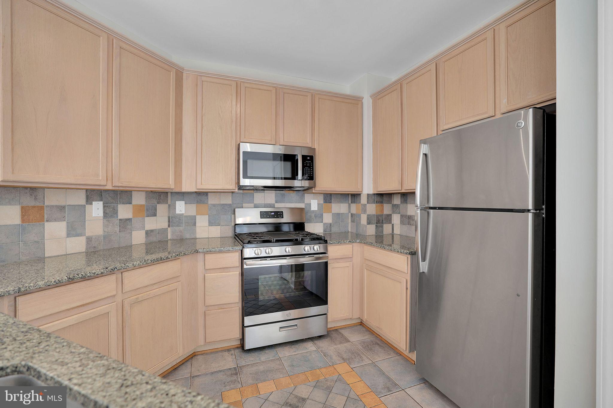 111 A Chevy Chase Street, Unit 111A Gaithersburg, MD 20878 - Photo 16 of 47 a kitchen with stainless steel appliances granite countertop a refrigerator stove a sink and dishwasher