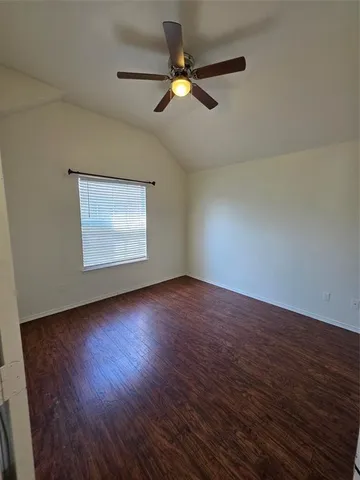 an empty room with wooden floor chandelier fan and windows