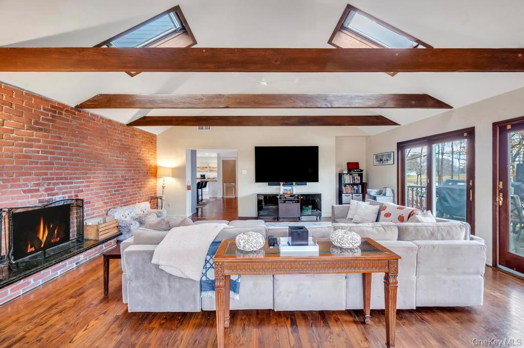 39 Bevin Road Northport, NY 11768 - Photo 20 of 44 Living area featuring a skylight, a fireplace, wood finished floors, and brick wall
