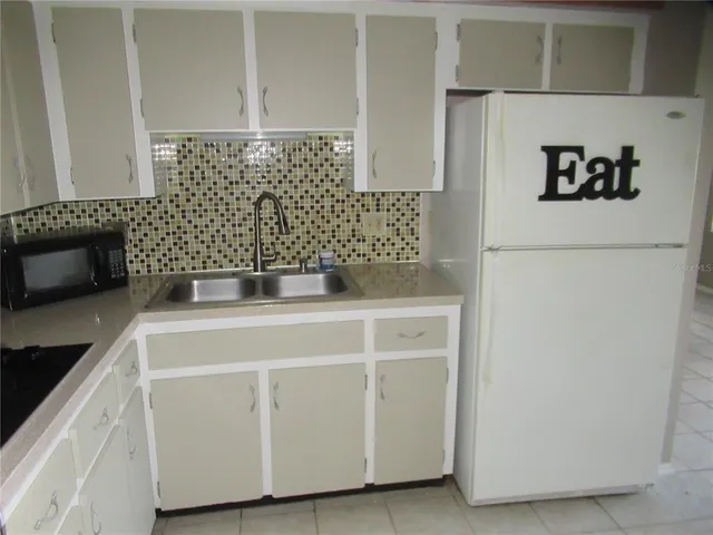 a kitchen with a refrigerator and white cabinets