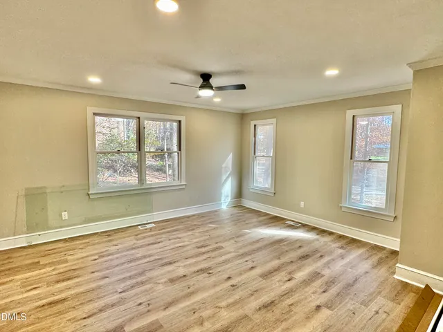 a view of an empty room with a window and wooden floor