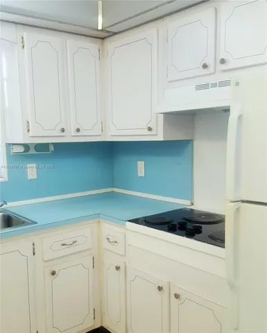 a kitchen with granite countertop white cabinets and a sink