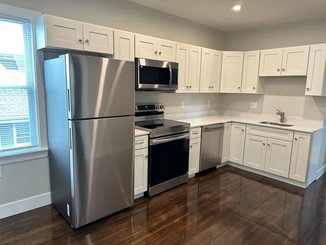 a kitchen with cabinets stainless steel appliances and a window