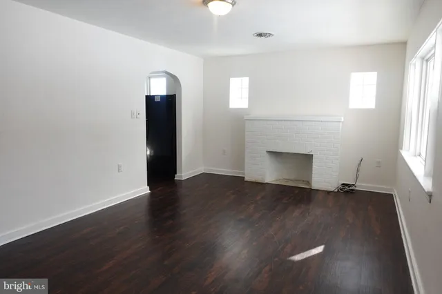 an empty room with wooden floor closet and windows