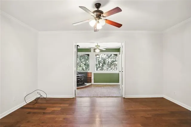 an empty room with wooden floor fan and windows