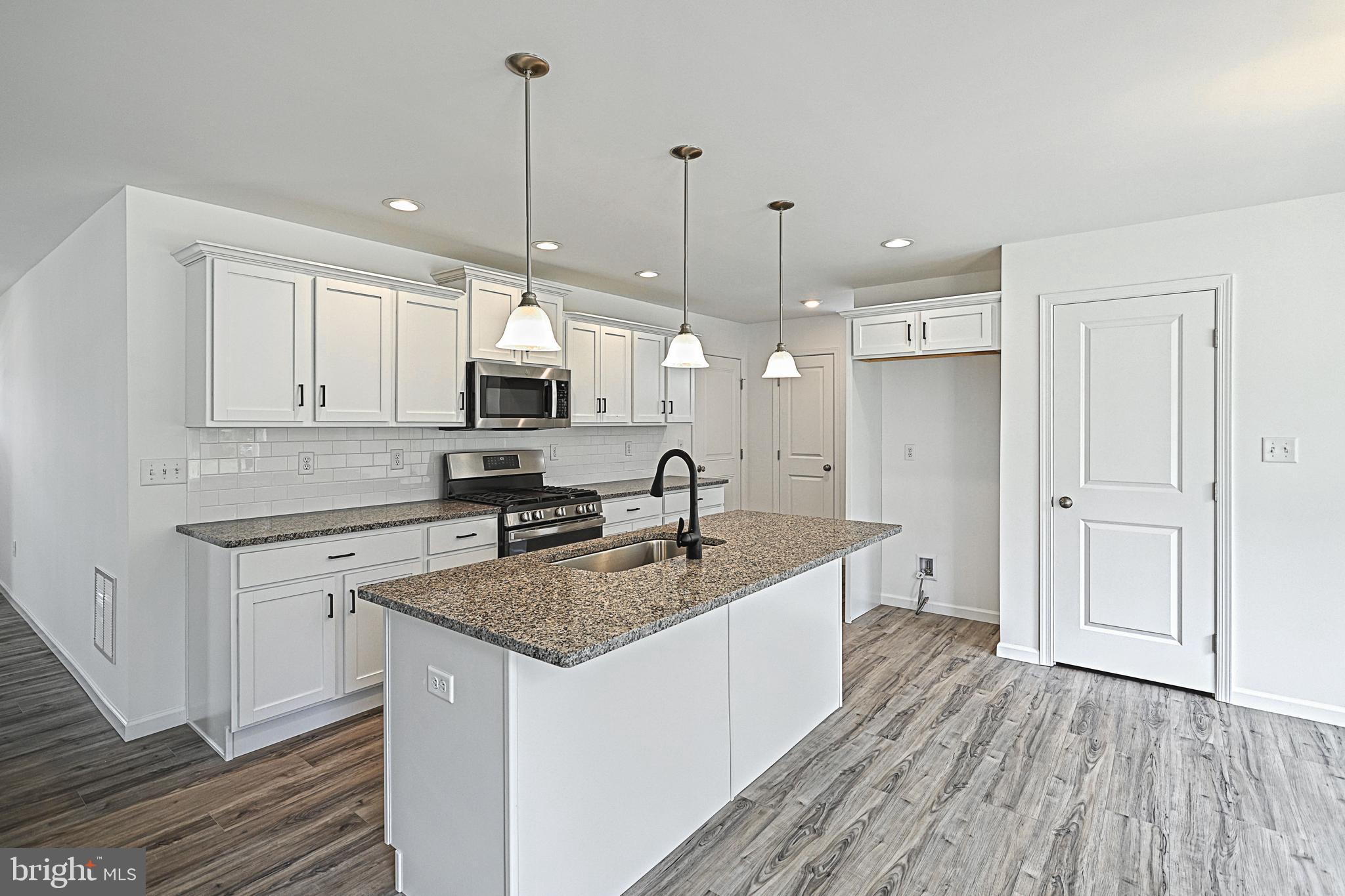 Meriwether Plan At Stone Mill Estates Duncannon, PA 17020 - Photo 4 of 28 a kitchen with stainless steel appliances granite countertop a sink stove and white cabinets with wooden floor