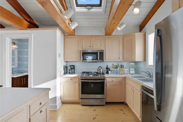 a kitchen with granite countertop a sink stainless steel appliances and white cabinets