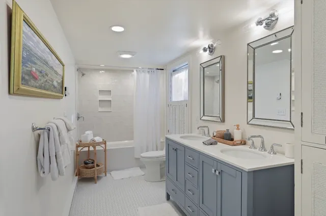 a bathroom with a double vanity sink mirror and toilet
