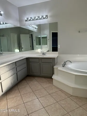 a spacious bathroom with a tub sink and mirror