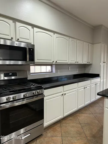 a kitchen with granite countertop white cabinets and stainless steel appliances