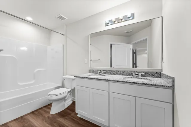 a bathroom with a granite countertop toilet a sink and a bathtub