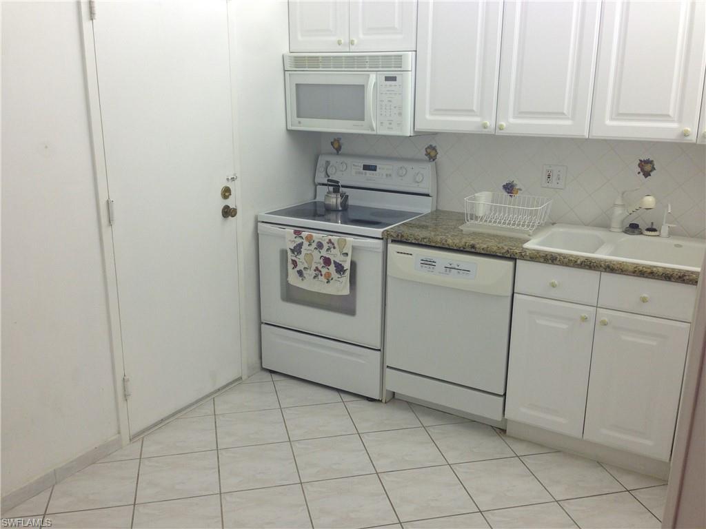3760 Inverrary Drive, Unit 1W Lauderhill, FL 33319 - Photo 4 of 32 Kitchen featuring white appliances, a sink, white cabinetry, light tile patterned floors, and backsplash