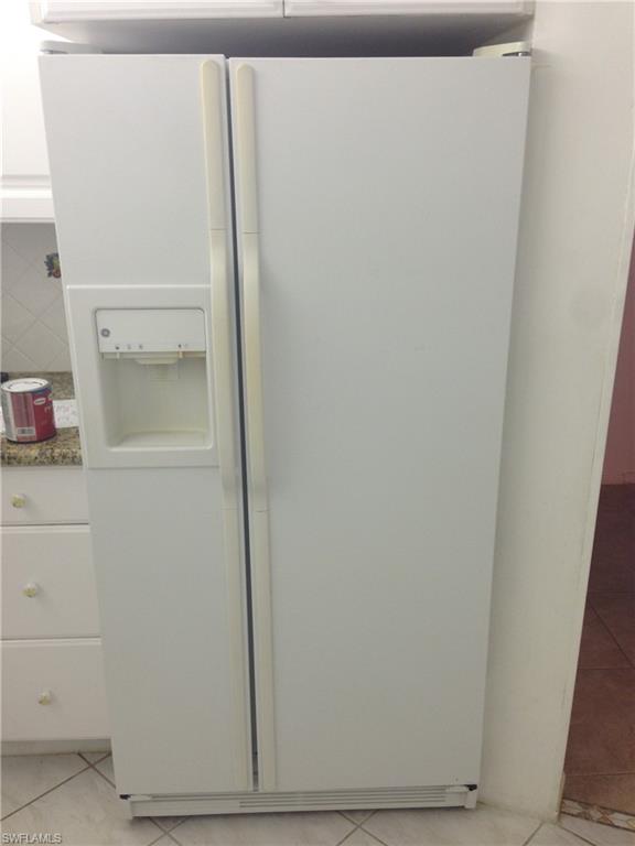 3760 Inverrary Drive, Unit 1W Lauderhill, FL 33319 - Photo 5 of 32 Kitchen view of white fridge with ice dispenser, white cabinetry, decorative backsplash, and dark stone countertops