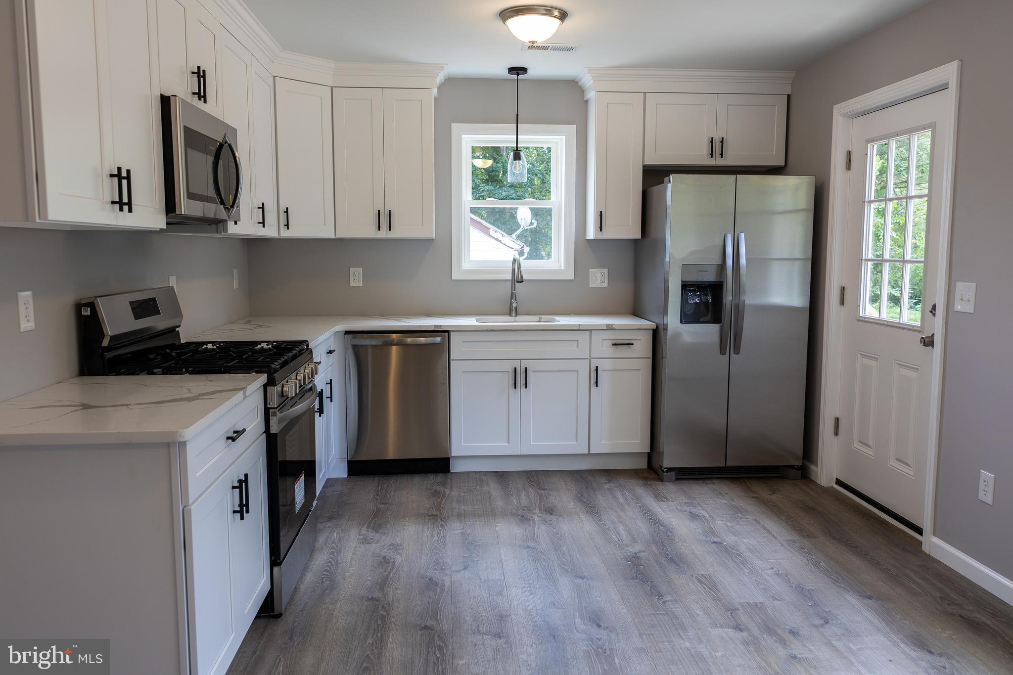 348 Colfax Street Bridgeton, NJ 08302 - Photo 3 of 26 a kitchen with stainless steel appliances granite countertop a refrigerator a sink dishwasher a stove and white countertops with wooden floor