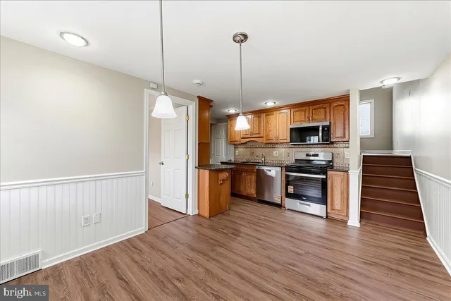 a kitchen with stainless steel appliances a stove top oven a sink and a wooden floor