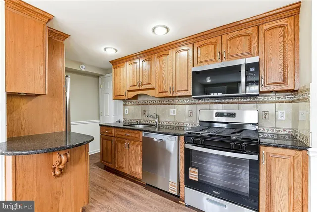 a kitchen with stainless steel appliances granite countertop a stove microwave and sink