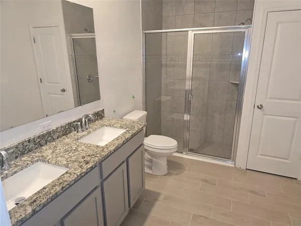 a bathroom with a granite countertop sink a toilet and shower
