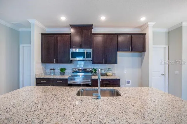 a kitchen with stainless steel appliances granite countertop a stove a sink and a refrigerator