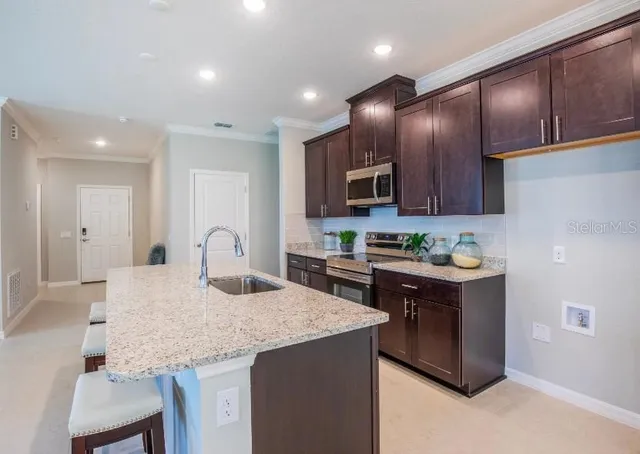 a kitchen with kitchen island granite countertop wooden cabinets and refrigerator