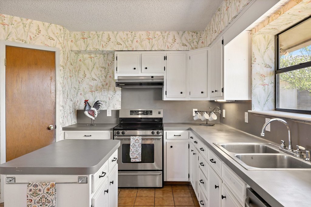 3410 West Ranch Road 152 Llano, TX 78643 - Photo 11 of 36 Kitchen featuring electric range, white cabinetry, wallpapered walls, a textured ceiling, and extractor fan