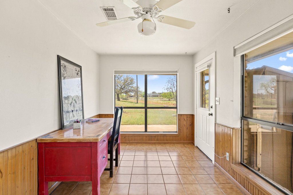 3410 West Ranch Road 152 Llano, TX 78643 - Photo 21 of 36 Office space featuring wooden walls, a wainscoted wall, a ceiling fan, plenty of natural light, and light tile patterned floors
