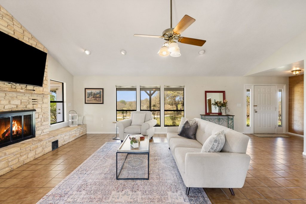 3410 West Ranch Road 152 Llano, TX 78643 - Photo 5 of 36 Living area featuring vaulted ceiling, ceiling fan, a fireplace, and tile patterned floors