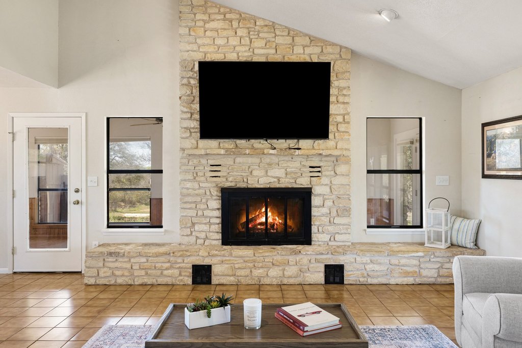 3410 West Ranch Road 152 Llano, TX 78643 - Photo 8 of 36 Living area with lofted ceiling, a stone fireplace, and light tile patterned floors