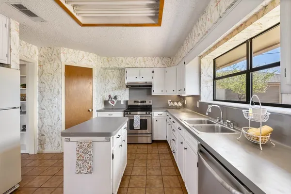 a kitchen with stainless steel appliances a sink a stove and white cabinets