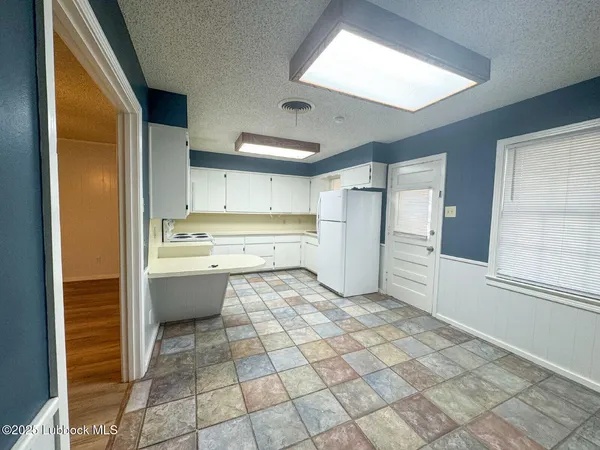 a large white kitchen with a sink and refrigerator