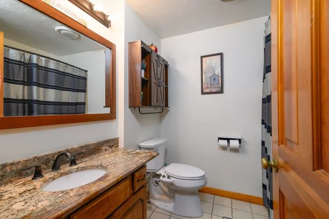 a bathroom with a granite countertop toilet sink and mirror