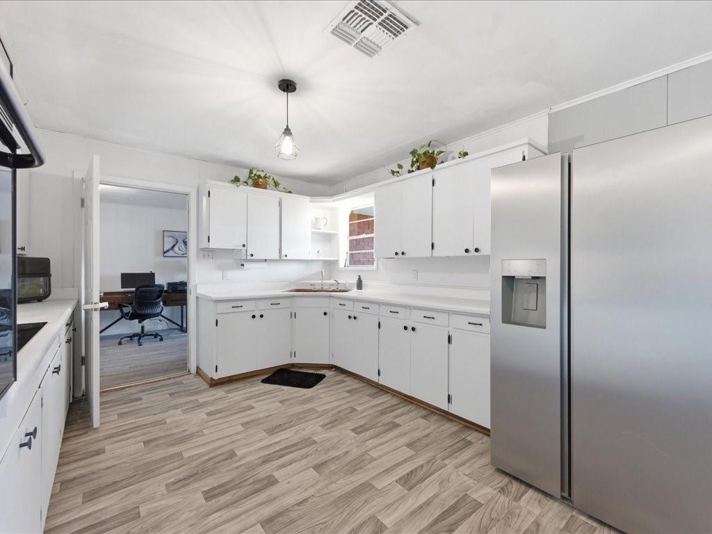 1085 Duke Road Kennard, TX 75847 - Photo 13 of 40 Kitchen featuring light wood-finish flooring, white cabinetry with dark hardware, and a stainless steel side-by-side refrigerator