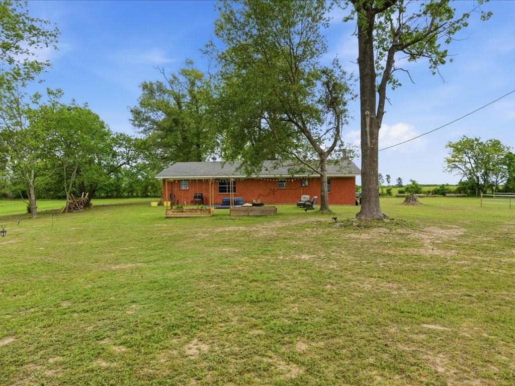 1085 Duke Road Kennard, TX 75847 - Photo 23 of 40 Expansive green lawn with mature trees and a brick exterior residence featuring a covered porch
