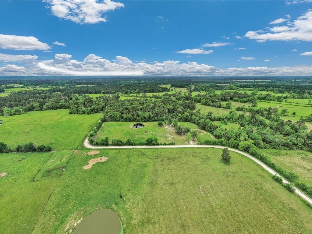 1085 Duke Road Kennard, TX 75847 - Photo 33 of 40 Expansive rural acreage featuring green pastures, mature trees, a private pond, and a winding dirt road