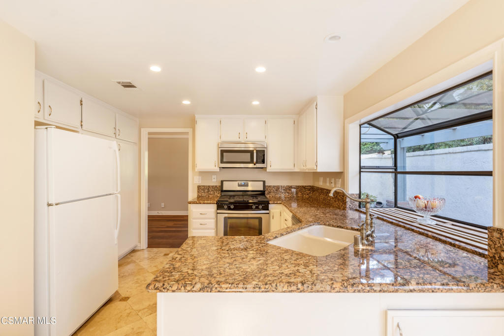 932 Thistlegate Road Oak Park, CA 91377 - Photo 11 of 25 a kitchen with a refrigerator a stove and a sink with wooden floor