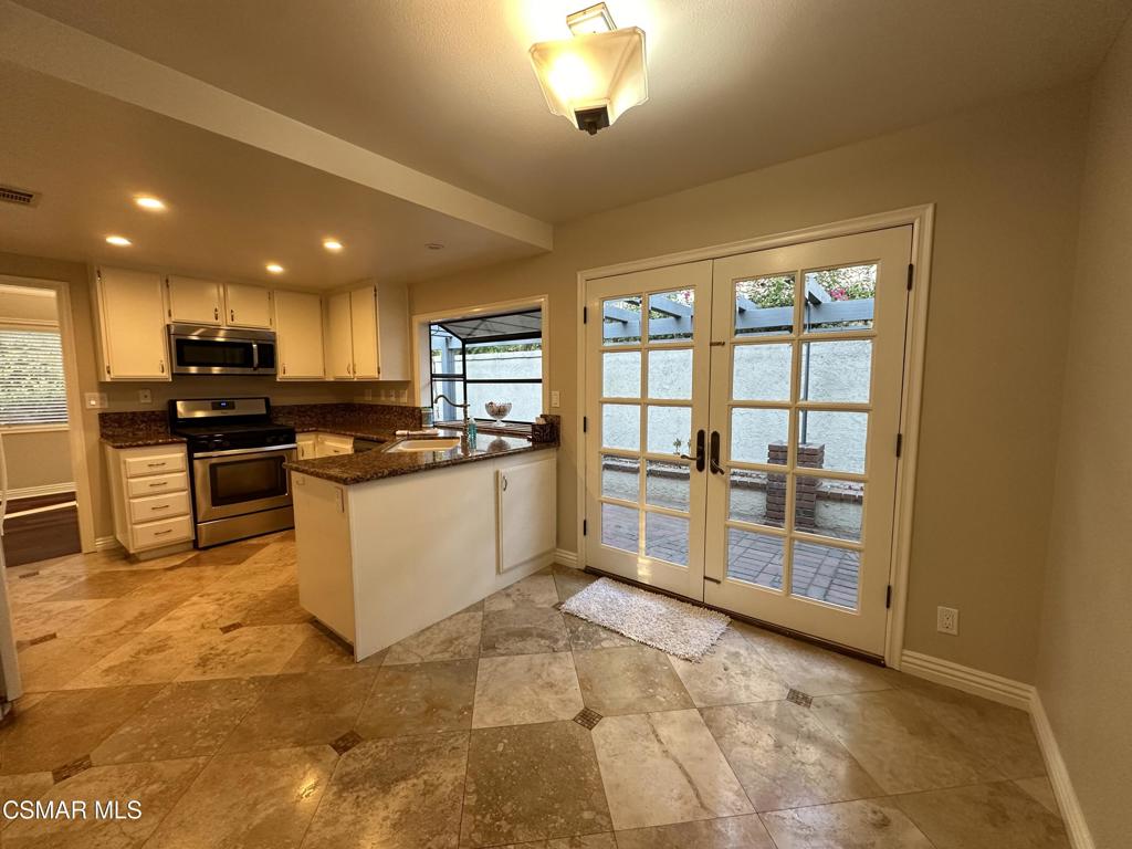 932 Thistlegate Road Oak Park, CA 91377 - Photo 12 of 25 a kitchen with stainless steel appliances granite countertop a stove top oven a sink a dining table and chairs